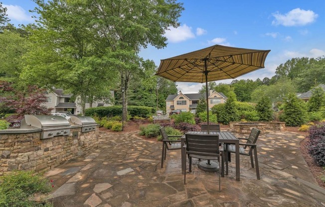 A patio with a table and chairs under an umbrella.