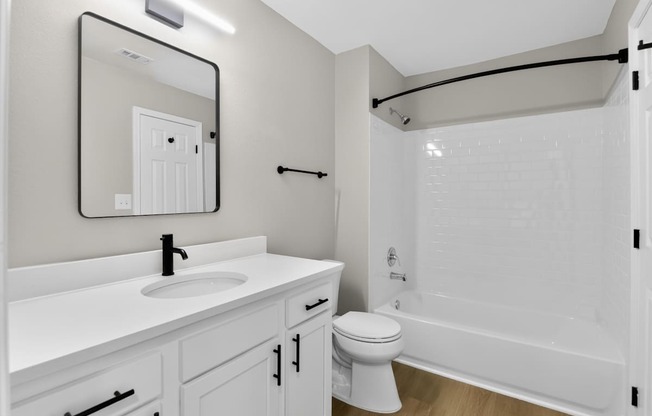 A white bathroom with a sink, toilet, and bathtub.