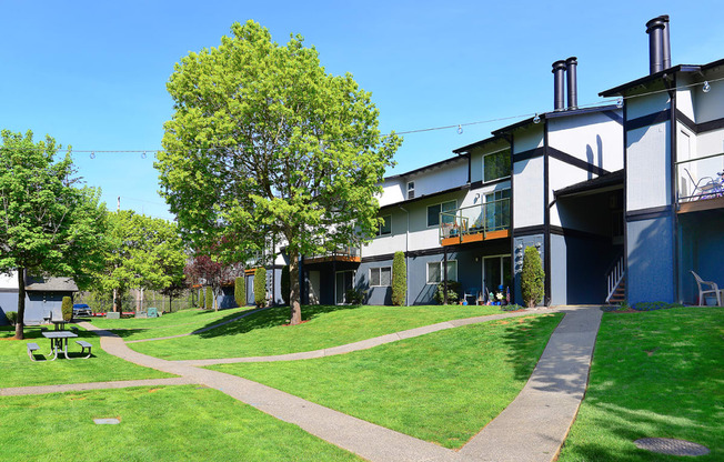 a grassy area with trees and buildings in the background