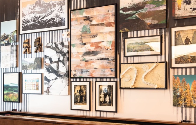 a wall of pictures on display in a gallery with a bench
