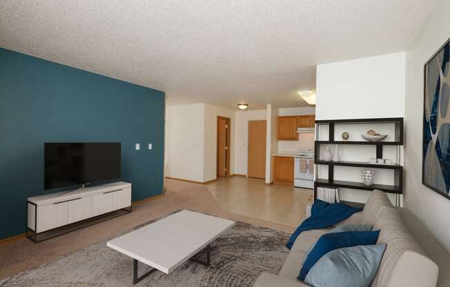 A living room with a couch and a coffee table and a televisio. Fargo, ND Pinehurst Apartments.