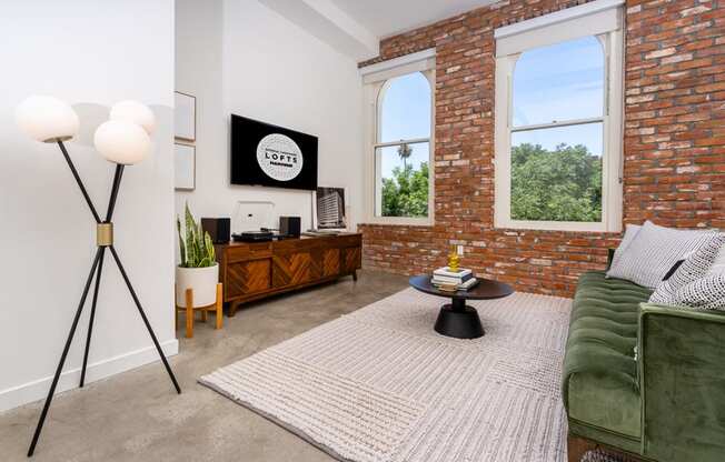 a living room with a green couch and a brick wall