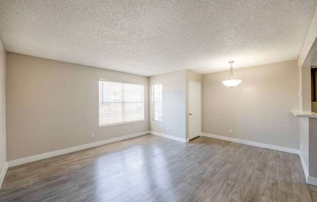 an empty living room with hardwood floors and a chandelier