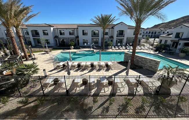 A pool surrounded by palm trees and lounge chairs.