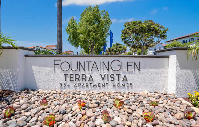 A wall with the text "Fountainglen Terra Vista 55+ Apartment Homes" on it.