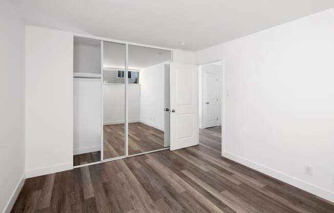 a bedroom with white walls and a hardwood floor