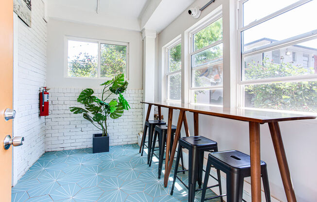 a long wooden table with black stools in a white room with large windows  at The Oasis on Cascade, Atlanta, GA