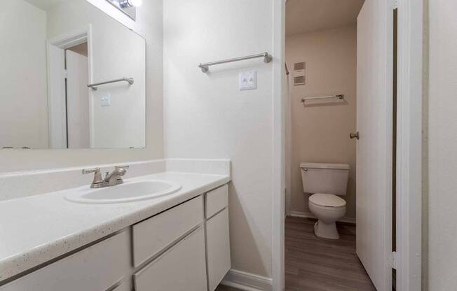 A white bathroom with a toilet and sink.at 2400 Briarwest Apartments, Texas