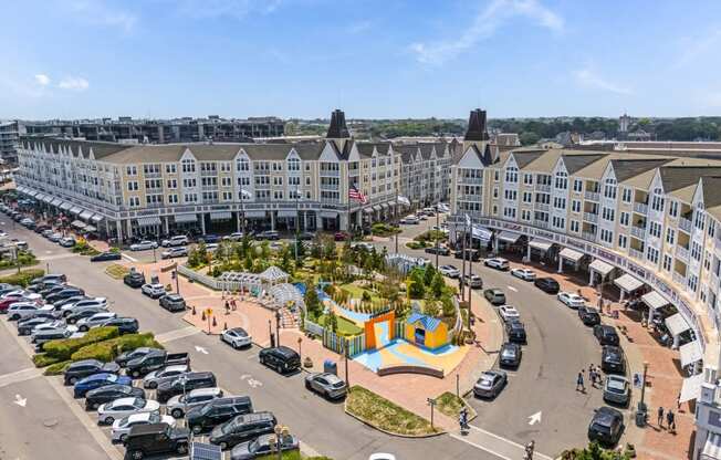 A view of a parking lot with cars and a colorful playground in the foreground.