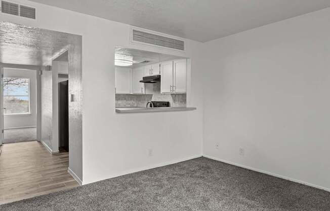 A sparsely furnished room with a kitchen area in the background.