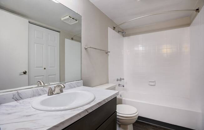 a bathroom with a sink toilet and shower and a mirror