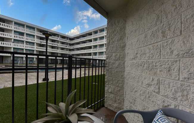 A balcony with a chair and a plant in front of a building.