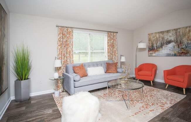 a living room with a couch and chairs and a window