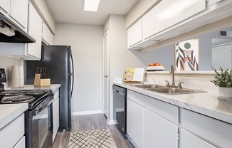 Pet-Friendly Apartments in West Houston, TX– Magnolia Terrace- A kitchen with a black refrigerator and white cabinets.
