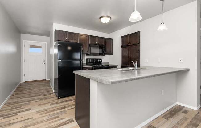 A kitchen with a black fridge and microwave.