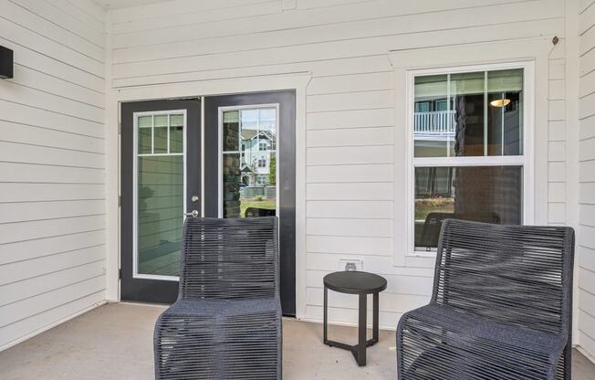 a front porch with two chairs and a small table