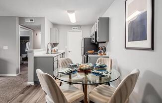 A modern kitchen with a glass dining table and chairs.