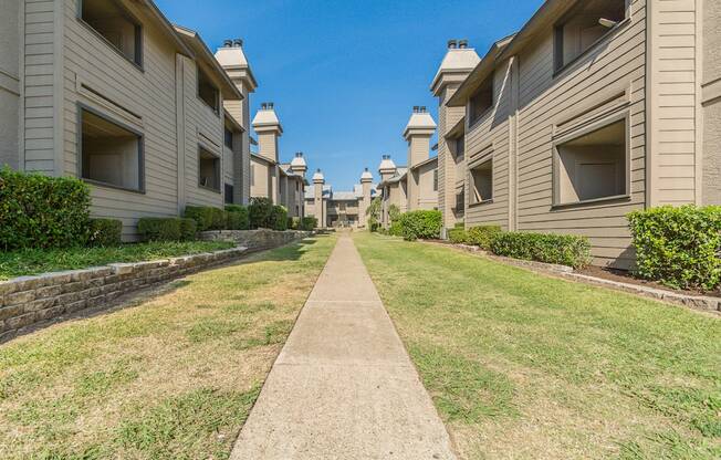 a grassy path between apartment buildings
