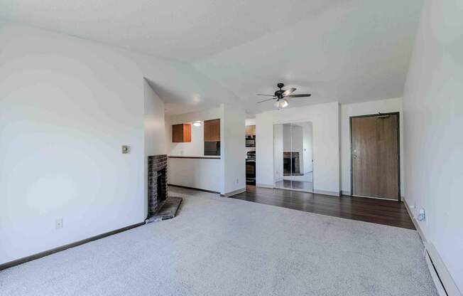 A spacious living room with a fireplace and a ceiling fan.