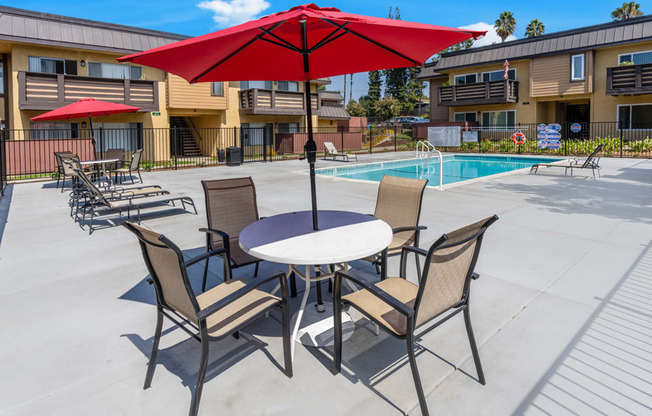 our apartments have a patio with a table and chairs and a pool