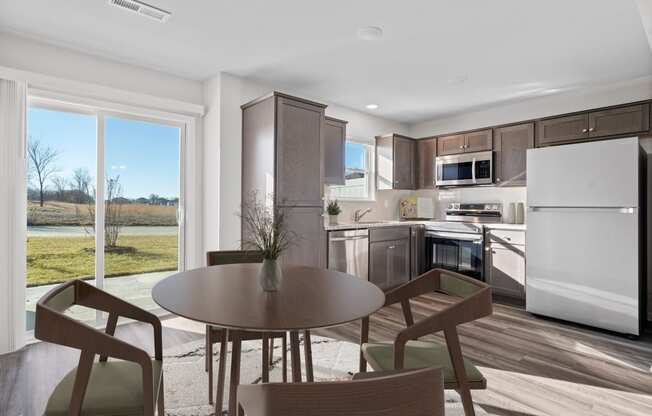 a dining room with a table and chairs and a kitchen with stainless steel appliances