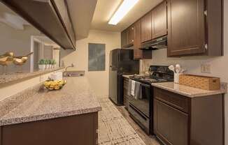 Model kitchen with brown cabinets and a black refrigerator at Pheasant Pointe Apartments, California, 95833