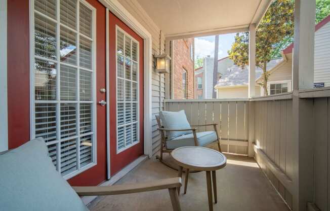 a porch with two chairs and a table