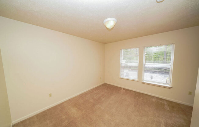 a bedroom with two windows and carpet