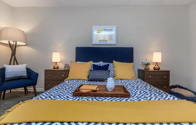 A bed with a yellow and blue blanket at Ashley Oaks Apartments in Greensboro, North Carolina
