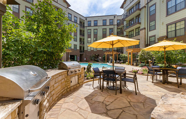 Grilling area with gas grills and patio seating with umbrellas,at 1010 Dilworth Apartments, Charlotte North Carolina