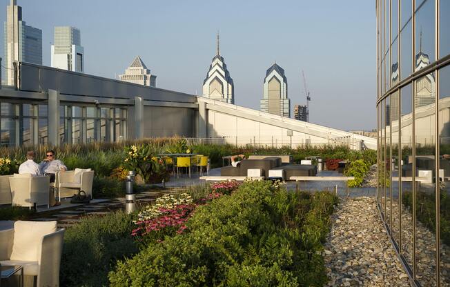 A rooftop garden with people sitting and a city skyline in the background.