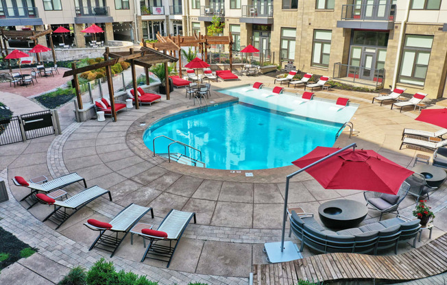 a swimming pool in the middle of a courtyard with chairs and umbrellas