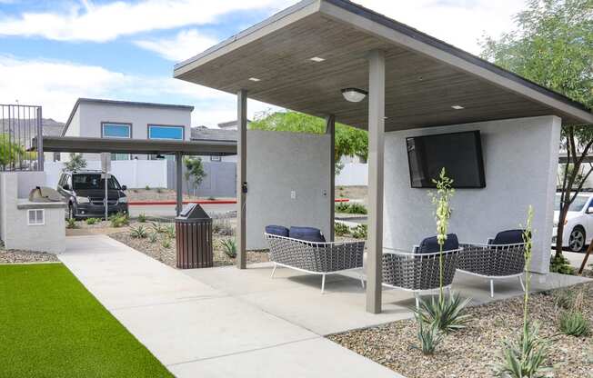 a patio with chairs and a television on the side of a house