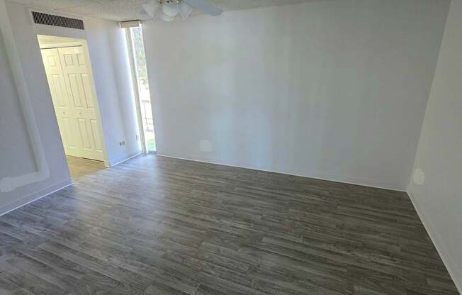 A room with a ceiling fan and wood flooring.