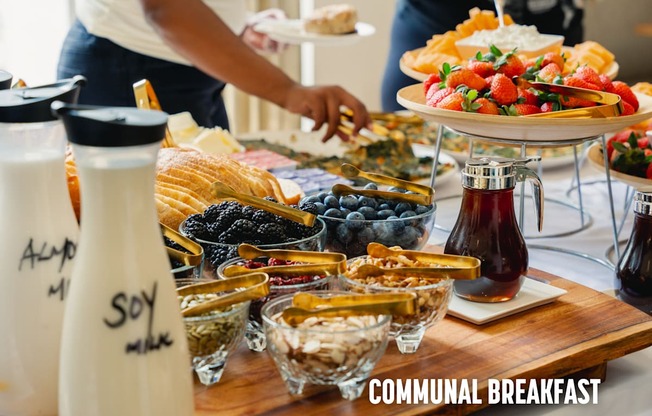 A communal breakfast table with various dishes and a sign that says