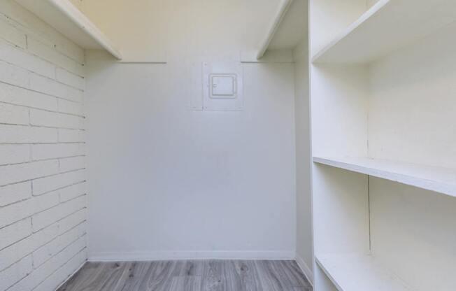 A white wall with a light switch and a wooden floor.