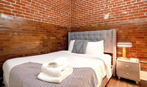 a bedroom with a bed and a brick wall