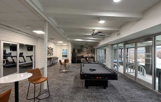 A room with a pool table and chairs.