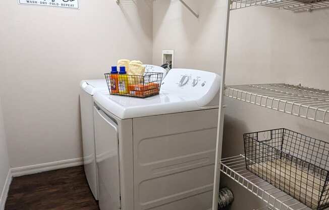 a walk in closet with a washer and dryer in it and a shelf