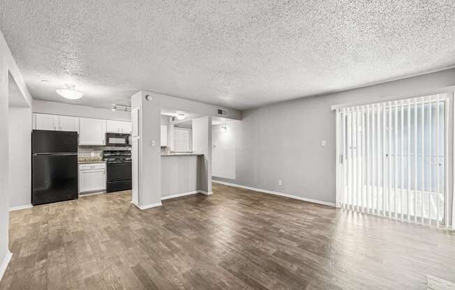 A spacious room with a kitchen area and a window with blinds.