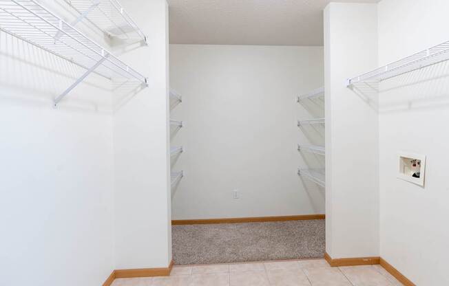 A laundry room with laundry hookups and shelves. Fargo, ND Stonebridge Apartments