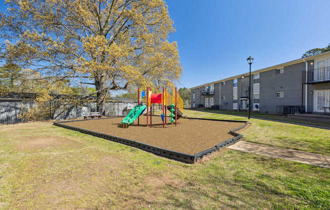 A playground with a slide and swings in a grassy area.