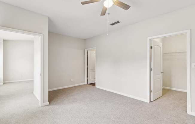 an empty bedroom with a ceiling fan and a closet