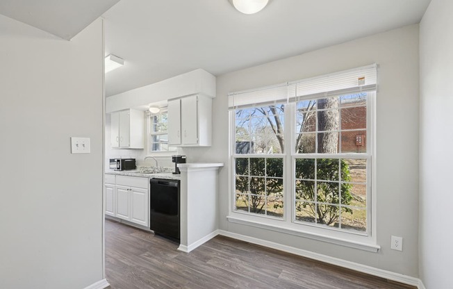 A kitchen with white cabinets and a black dishwasher.
