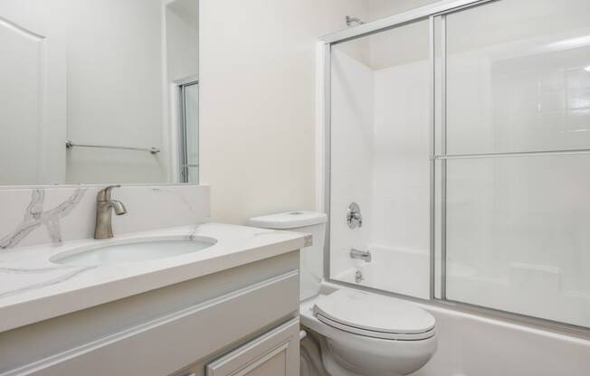 a white bathroom with a shower toilet and sink