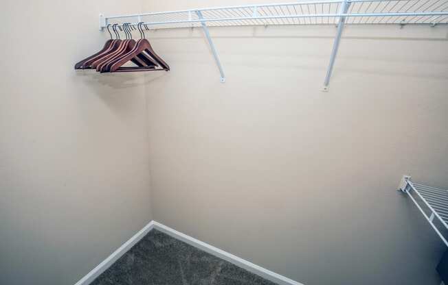a walk in closet with a white wall and a rack and hangers