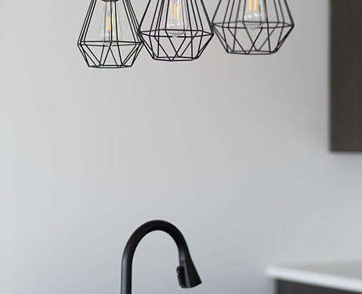 a kitchen sink with a black faucet and three lights at The Landing at 1001 NP, Fargo, North Dakota 58102