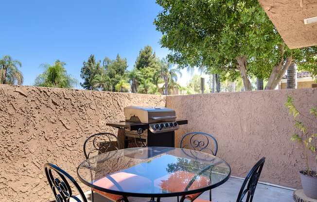 a patio with a table and chairs and a grill