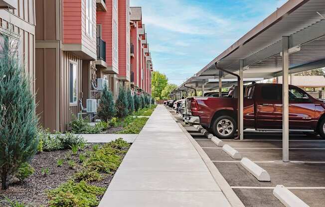 A red car is parked in a parking lot next to a building.