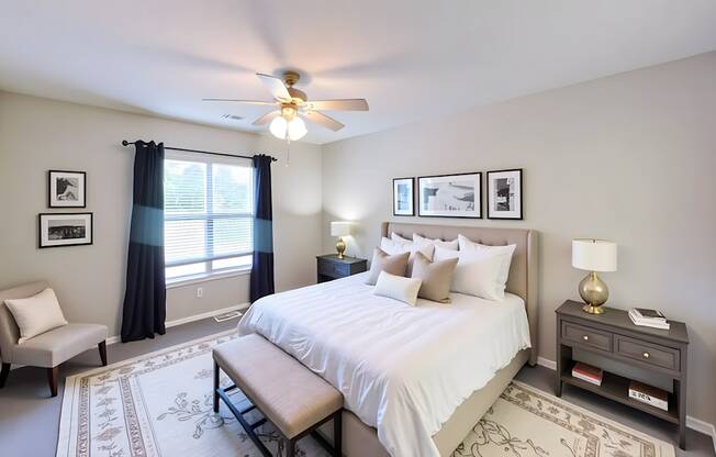 A bedroom with a bed, nightstand, chair, and pictures on the wall.